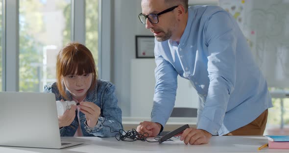 Mature Teacher Helping Schoolgirl with Engineering Project at School