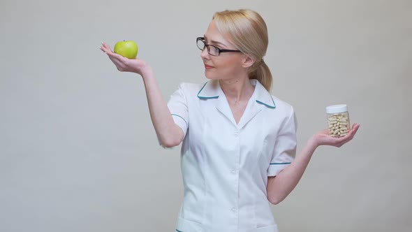 Nutritionist Doctor Healthy Lifestyle Concept - Holding Organic Green Apple and Jar of Vitamin Pills