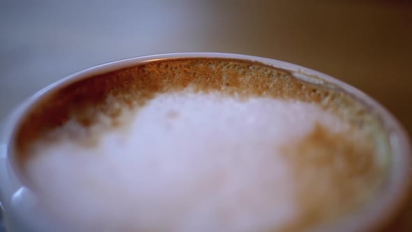 Cup of Cappuccino with White Foam on the Wooden Table in the Restaurant. Close-up