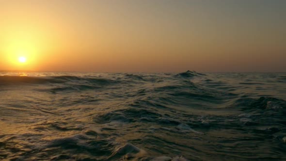 Romantic sunset over sea water, Low-angle sea water surface fpv poving backward in slow motion
