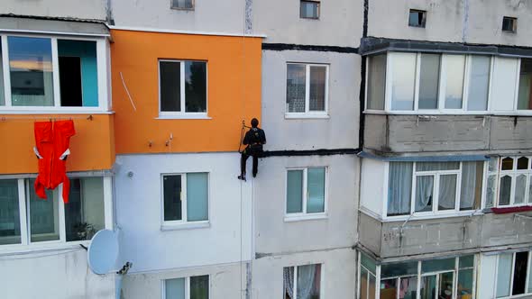 Painting and Decorating Buildings. Worker on a Construction Site of a High-rise Building. Dangerous