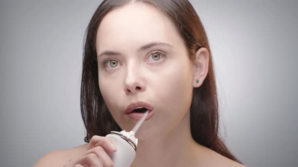 Woman Cleaning Teeth with Water Flosser 