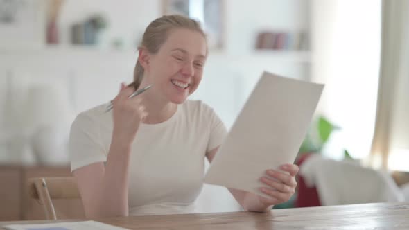 Beautiful Young Woman Celebrating Success on Document in Office