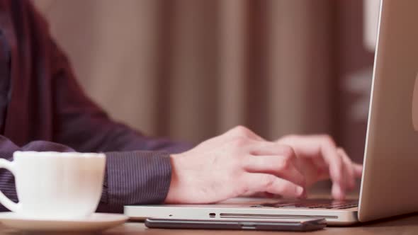 Male Hands Typing a Text on His Laptop on a Coffee Break