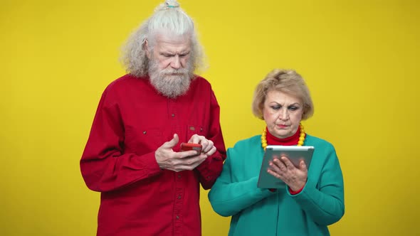 Portrait of Absorbed Senior Man and Woman Surfing Internet Messaging Online Ignoring Each Other