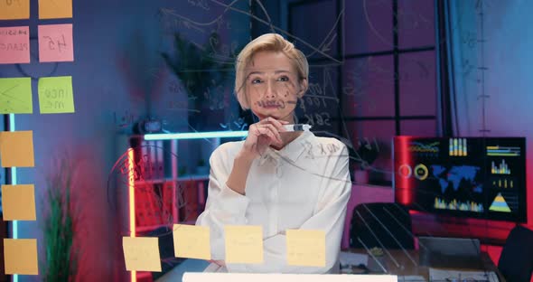 woman standing in front of glass board and writing on it needed notes for her business project