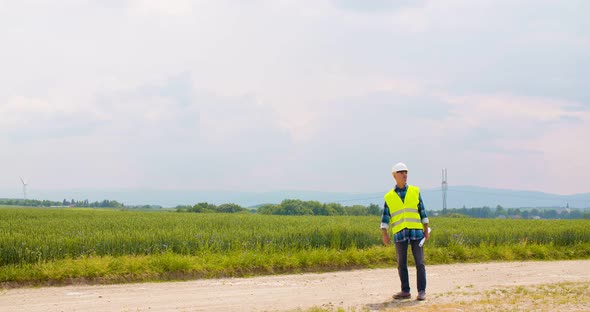 Engineer with Blueprint Analyzing Farm Against Sky