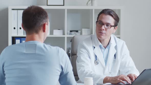 Male pediatrician is examining young man. Doctor and patient in medical office in clinics.