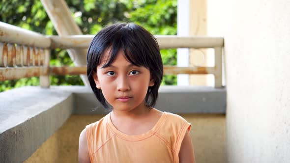 Young Southeast Asian boy alone outdoors smiling and being genuine looking into the camera on a brig