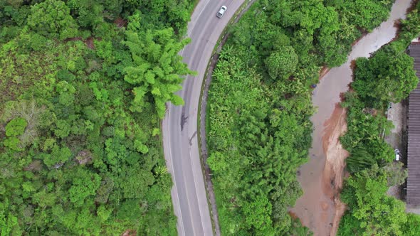 Topdown following car driving along tropical vegetation road, Small stream of water. Brazil