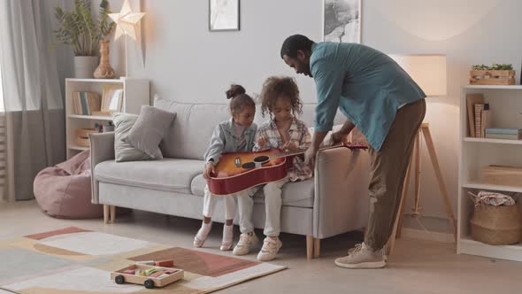 Father and Daughters Playing Guitar at Home