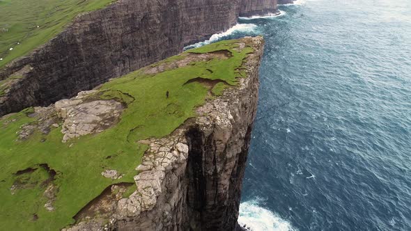 Aerial view of woman walking on the edge of tourists English Slave cliff.