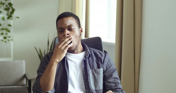 Portrait of Afro American Guy in Casual Clothes Sitting at Table at Home or Office Feeling Bored