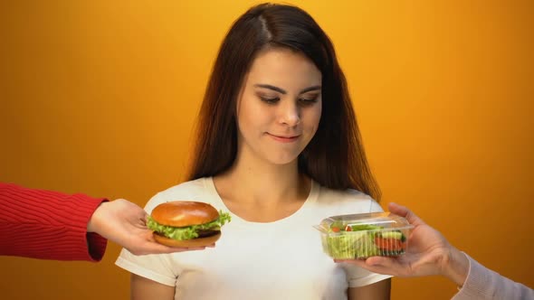 Hungry Girl Choosing Hamburger Instead of Salad, Cheap Junk Food vs Healthy Diet