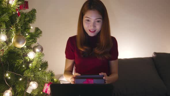 Young Asia female using tablet video call talking with couple with X'Mas present box, Christmas tree