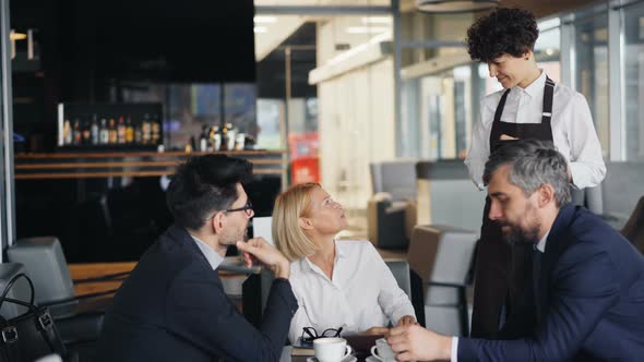 Waitress Taking Order From Group of Businesspeople Men and Lady Talking at Table