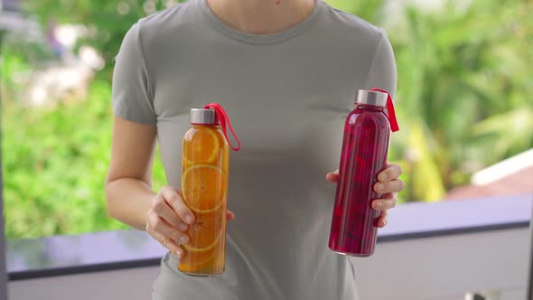 A Woman Holds Two Bottles with Kombucha Drink in Her Hands Which Have Different Flavors Orange and