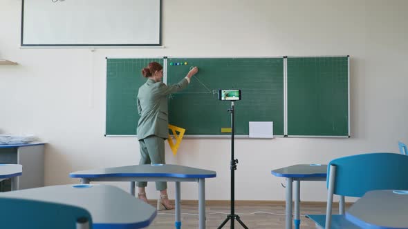 Online Education Pedagogue in Glasses with Ruler Near Blackboard Using Mobile Phone Camera Recording