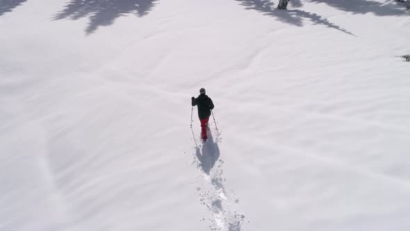 Aerial Following Man Snowshoeing Alone In Mountain Backcountry Powder Snow