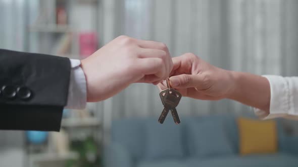 Close Up Of Real Estate Agent's Hand Giving The Keys To A Woman In The House For Sale