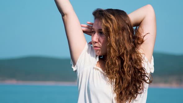 girl in a white sundress on the background of the sea on a bright sunny day