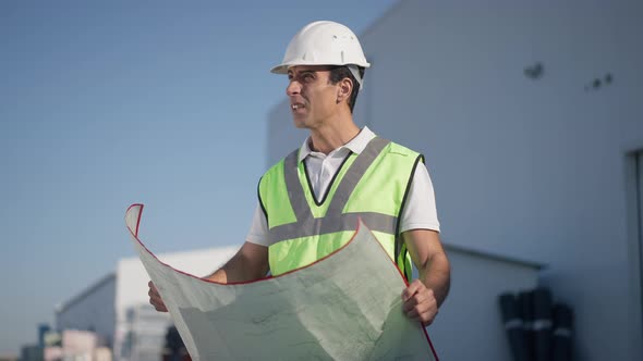 Thoughtful Professional Middle Eastern Engineer Architect Examining Blueprint Outdoors in Slow