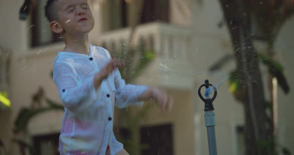 Cute Happy Child Playing with Garden Sprinkler on Summer Hot Day