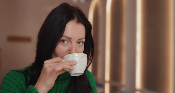 Woman Drinks Coffee Sitting in Cafe