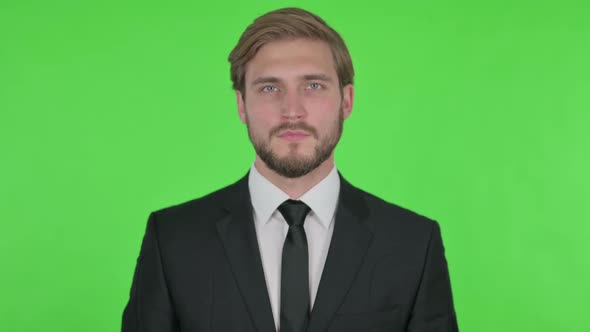 Serious Young Businessman on Green Background