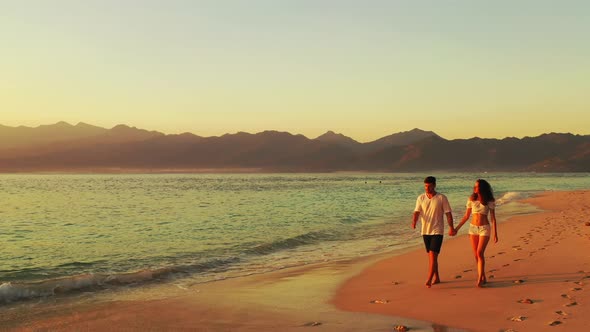 Young couple enjoying summer vacation on tranquil exotic beach on tropical islands surrounded by bea