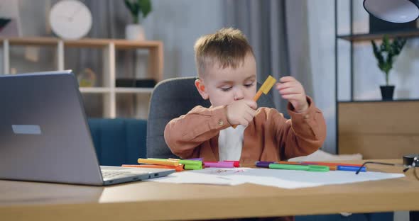 Boy Sitting at His Workplace and Drawing Elementary Picture with Felt-tip Pens