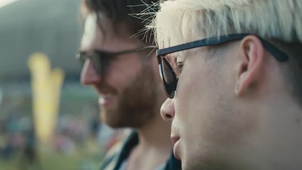 Close up of two young caucasian men having fun on music festival while drinking beer. Shot with RED