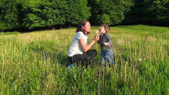 Mother and Kid Blowing Dandelion Flower