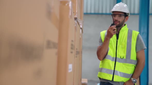 Professional Cargo Worker Talks on Portable Radio to Contact Another Worker