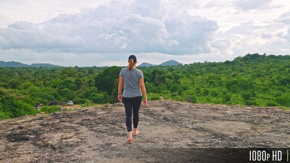 Woman Walking Towards Forest Clearing with Panorama View of the Jungle and Sky