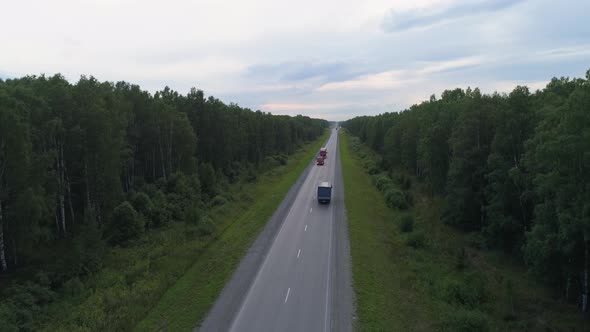 Drone aerial shot of a trucks and cars on the summer forest road near hills 11