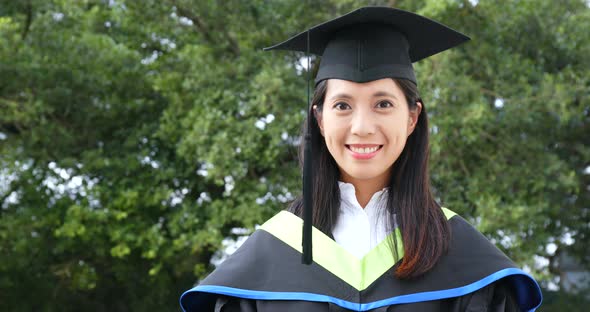 Asian woman wearing graduation gown