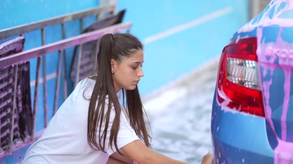 A Young Blonde Woman Washes Her Car