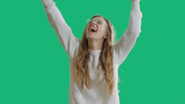 Portrait of a Joyful Happy Teenage Girl Is Celebrating Success While Dancing Isolated Over Green