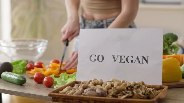 Closeup Go Vegan on Almond Nuts with Unrecognizable Woman Chopping Bell Pepper for Salad at