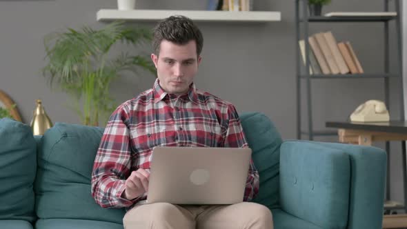 Man with Laptop Celebrating Success on Sofa