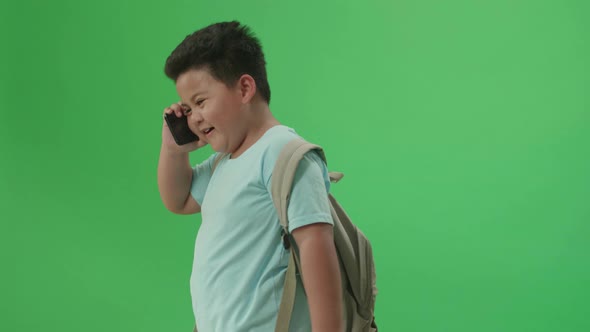 Asian Boy Student Talking On Mobile Phone And Walking To School On Green Screen Chroma Key