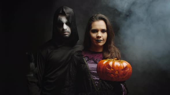 Young Woman Dressed Up Like a Witch Next To a Dark Grim Reaper