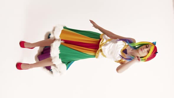 Young Caucasian Woman Cosplayer Moves with Charm in Her Rainbow Skirt and White Top Vertical Shot