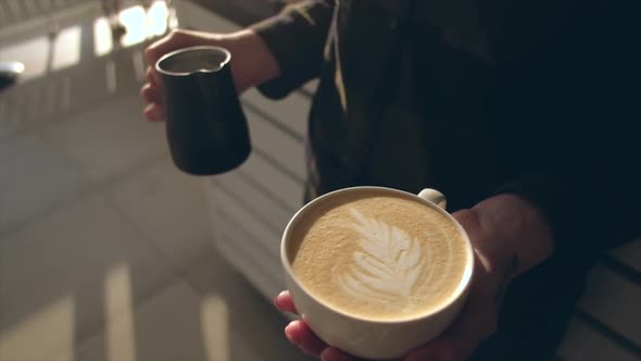 Close up of barista holding aromatic cappuccino. Coffee ready for sale.