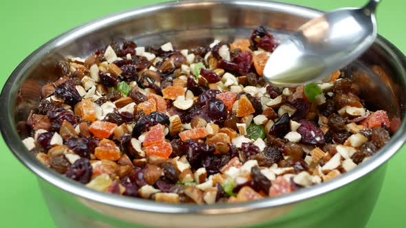 Pouring the rum over candied fruits and nuts. Rum-soaked dried fruit and nuts mixture