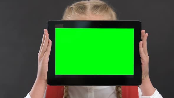 Schoolgirl Holding Tablet PC With Green Screen in Front of Face, Online Lessons