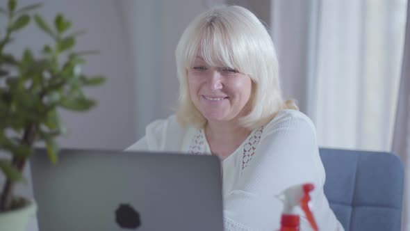 Close-up of Mature Caucasian Woman Surfing Internet and Smiling. Happy Female Retiree Using Gadget