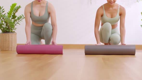 Close up of two young athletes unfolding yoga mat prepare for exercise at home studio. Woman rolling