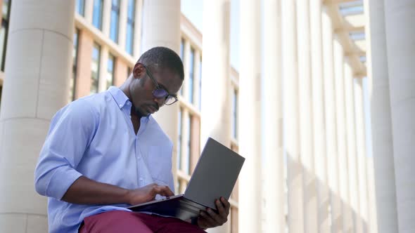 Young African American Businessman Working on Laptop Outside Business Center
